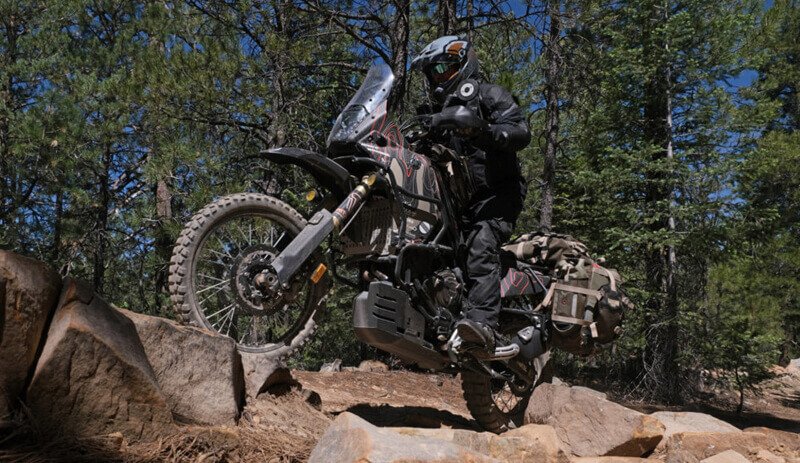 Off-road motorcycle climbing a steep rocky slope with luggage
